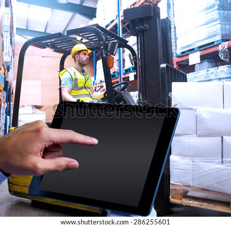 Man using tablet pc against focused driver operating forklift machine