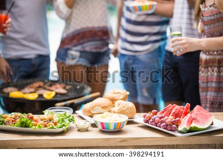 Table laid with hamburgers, fruits and barbecue for outdoors barbecue party