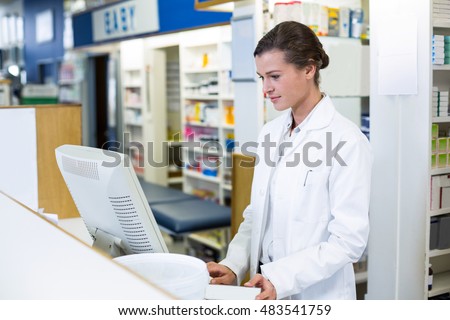 Pharmacist making prescription record through computer in pharmacy