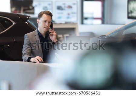 Car salesperson talking on landline phone while working in showroom