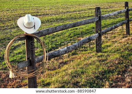 American West Rodeo Vintage Cowboy Hat And Authentic Lariat Lasso Hanging On A Ranch Fence Post American West Rodeo Vintage Cowboy Hat And Authentic Lariat Lasso Hanging On A Ranch Fence Post