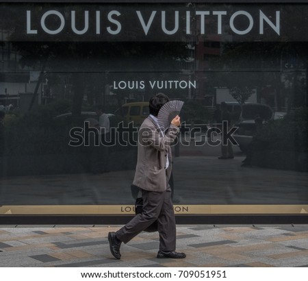 TOKYO, JAPAN - SEPTEMBER 1ST, 2017. Japanese white collar workers or salaryman walking in front of Louis Vuitton outlet at Tokyo station.