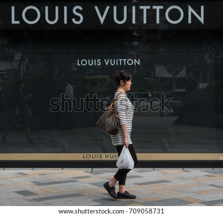 TOKYO, JAPAN - SEPTEMBER 1ST, 2017. Woman walking in front of Louis Vuitton outlet at Tokyo Station.