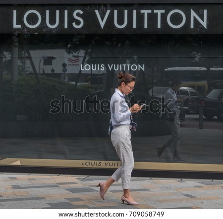 TOKYO, JAPAN - SEPTEMBER 1ST, 2017. Woman walking in front of Louis Vuitton outlet at Tokyo Station.
