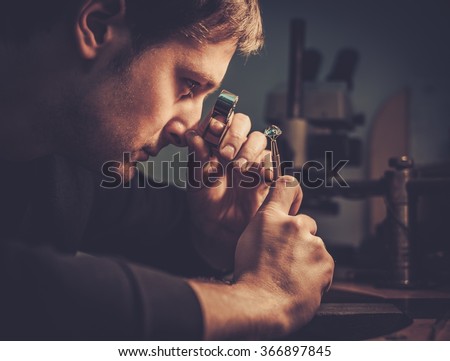Jeweler looking at the ring through microscope in a workshop.
