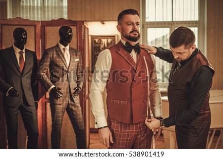 Tailor measuring client for custom made suit tailoring