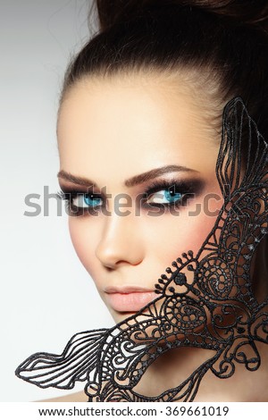Close-up portrait of young beautiful woman with smoky eyes and lacy black mask