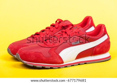 Varna , Bulgaria - JUNE 17, 2017. Red PUMA sport shoes on yellow background. Puma, a major German multinational company. Product shot
