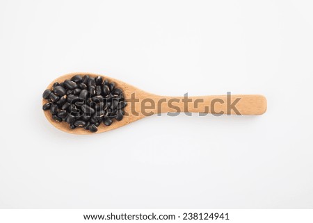 Black beans with wooden spoon on white background
