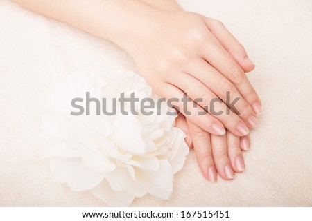 Beautiful hand with perfect nail french manicure and white flower