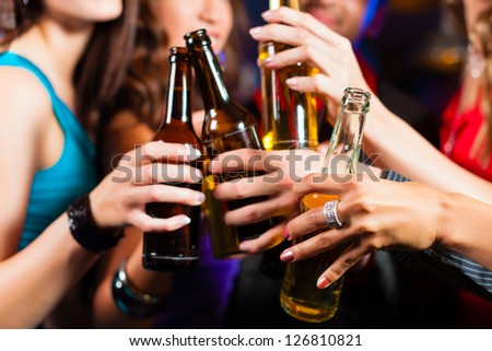 Group of party people - men and women - drinking beer in a pub or bar - stock photo