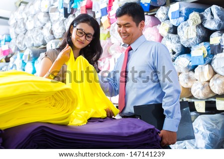 Indonesian textile workers choosing some colorful fabrics in a asian storehouse