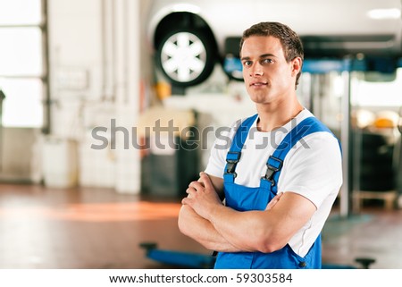 Auto mechanic standing in his workshop in front of a car on a hoist
