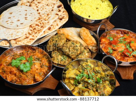 Indian food with curries, rice, naan bread, samosas and pakora. - stock photo