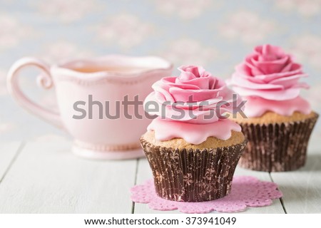 Cupcakes with sweet rose flowers and a cup of tee