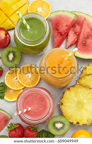 Smoothie jars surrounded by sliced fruits and berries