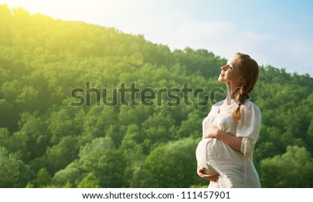 young happy pregnant woman relaxing and enjoying life in nature