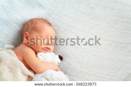 Cute newborn baby sleeps with a toy teddy bear white