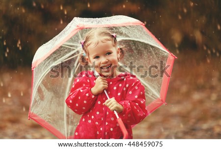 happy child girl laughing with an umbrella in the rain