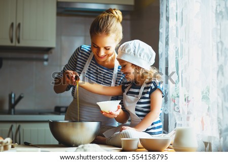 happy family in the kitchen. mother and child daughter preparing the dough, bake cookies