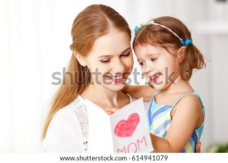 Happy mother's day! Child daughter congratulates moms and gives her a postcard and flowers tulips