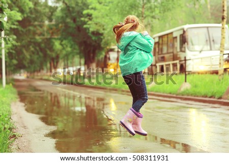 girl jumping in puddles spring rain