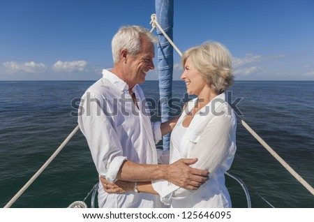 stock photo a happy senior couple embracing at the front or bow of a sail boat on a calm blue sea looking to a 125646095