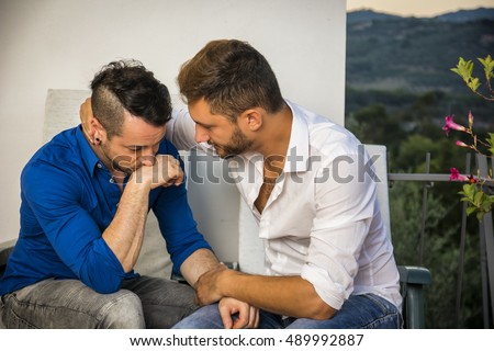 Sad depressed unhappy gay couple sitting on the sofa and Sad depressed unhappy gay couple sitting on the sofa and