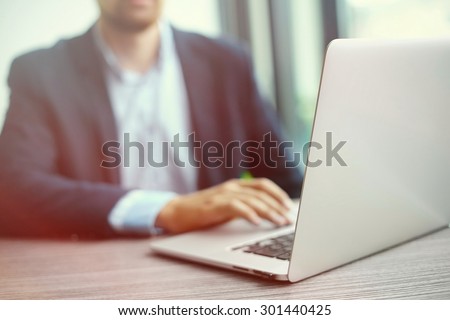 Young man working with laptop, man's hands on notebook computer, business person at workplace