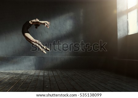 Professional ballet dancer performing in the dark lighted room