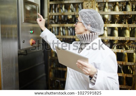 Control staff of fish factory choosing working regime of smoking machine
