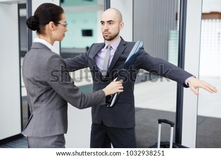 Female airport security using scanner to check one of passengers before flight