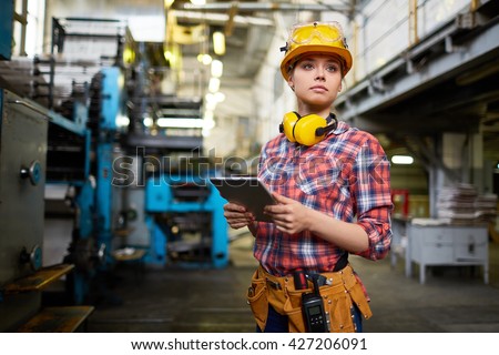 Pretty female student doing practical work at factory