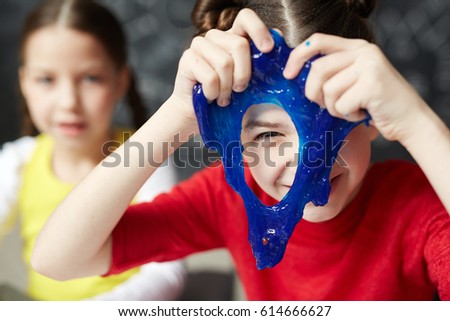 Happy kid looking through hole in blue slime