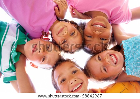 Below view of happy children embracing each other and smiling at camera