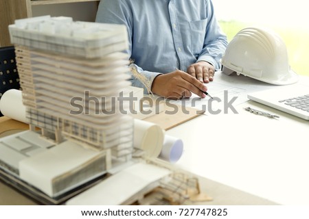 Architect or engineer hand on the table with home model