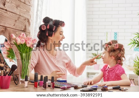 Happy loving family. Mother and daughter are doing hair, manicures, doing your makeup and having fun. Mother and daughter sitting at dressing table at house.