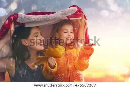 Mother and her child girl playing together on autumn walk in nature outdoors. Happy loving family having fun.