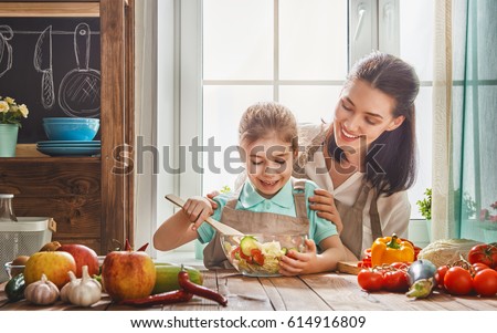 Healthy food at home. Happy family in the kitchen. Mother and child daughter are preparing the vegetables and fruit.