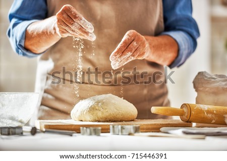Close up view of baker is working. Homemade bread. Hands preparing dough on wooden table.