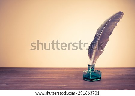 Vintage old quill pen, inkwell on wooden table. Retro style filtered photo