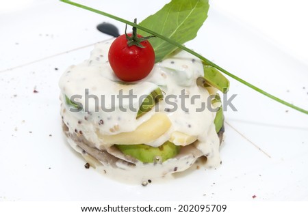 Herring salad with avocado sauce on a plate in a restaurant - stock photo
