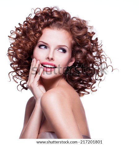 Beautiful smiling thoughtful woman with curly hair posing at studio over white background.