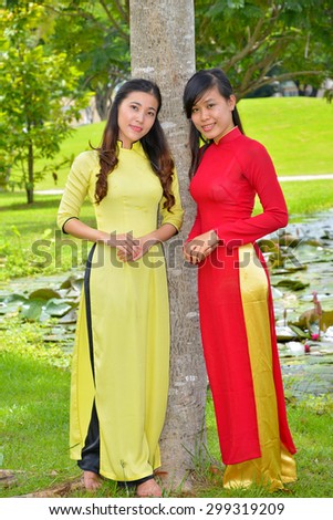 Portraits of two pretty girls wearing Ao Dai (Vietnam nation dress) in park