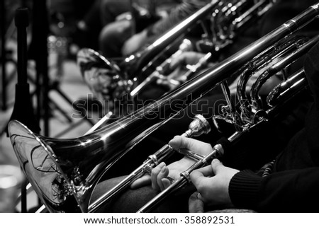 Trombones in the hands of the musicians in the orchestra in black and white Trombones in the hands of the musicians in the orchestra in black and white