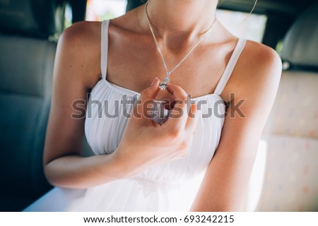 Girl in a white dress with a silver chain around her neck
The bride fixes a decoration of a jewel on the neck
Stylish fashionable diamond suspension
girl's neck pendant
pendant for women's neck