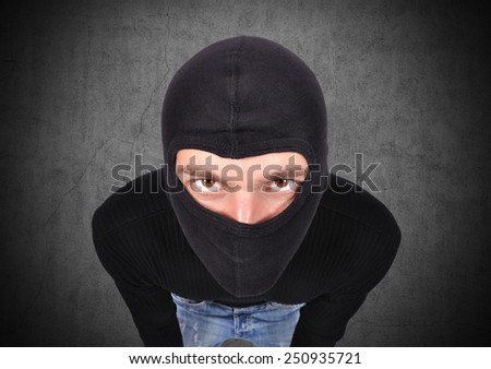 terrorist in mask on a gray wall background - stock photo