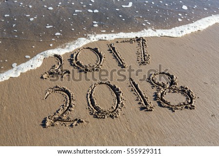 New Year 2018 is coming concept - inscription 2017 and 2018 on a beach sand, the wave is starting to cover the digits 2017