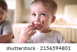 Small photo of children eat chocolate. dirty little baby kids in the kitchen eating chocolate in the morning. happy family lifestyle eating sweets kid dream concept. baby dirty face eating chocolate cocoa