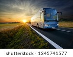 Bus traveling on the asphalt road in rural landscape at sunset                               